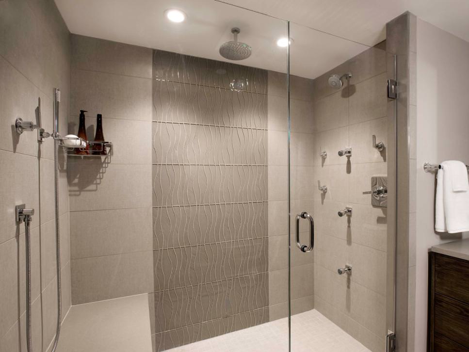 دکوراسیون حمام بزرگ با اتاق دوش شیشه ای و دوش بارانی که روی سقف آن چراغ سقفی توکار ضد آب نصب شده است